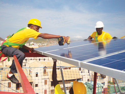 workers on a rooftop in West Africa, installing solar panels