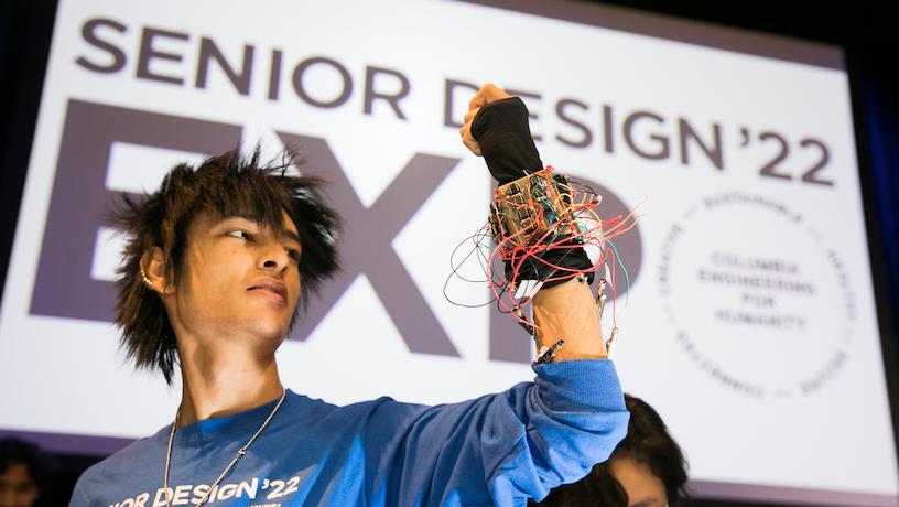 A Columbia Engineering student brandishes a glove covered in circuitry and wires for the 2022 Senior Design Expo.