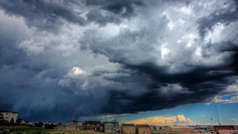 A massive, dark cloud approaching a residential neighborhood