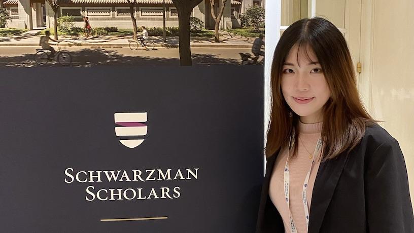 Helen Yang standing next to a plaque that reads "Schwarzman Scholars"