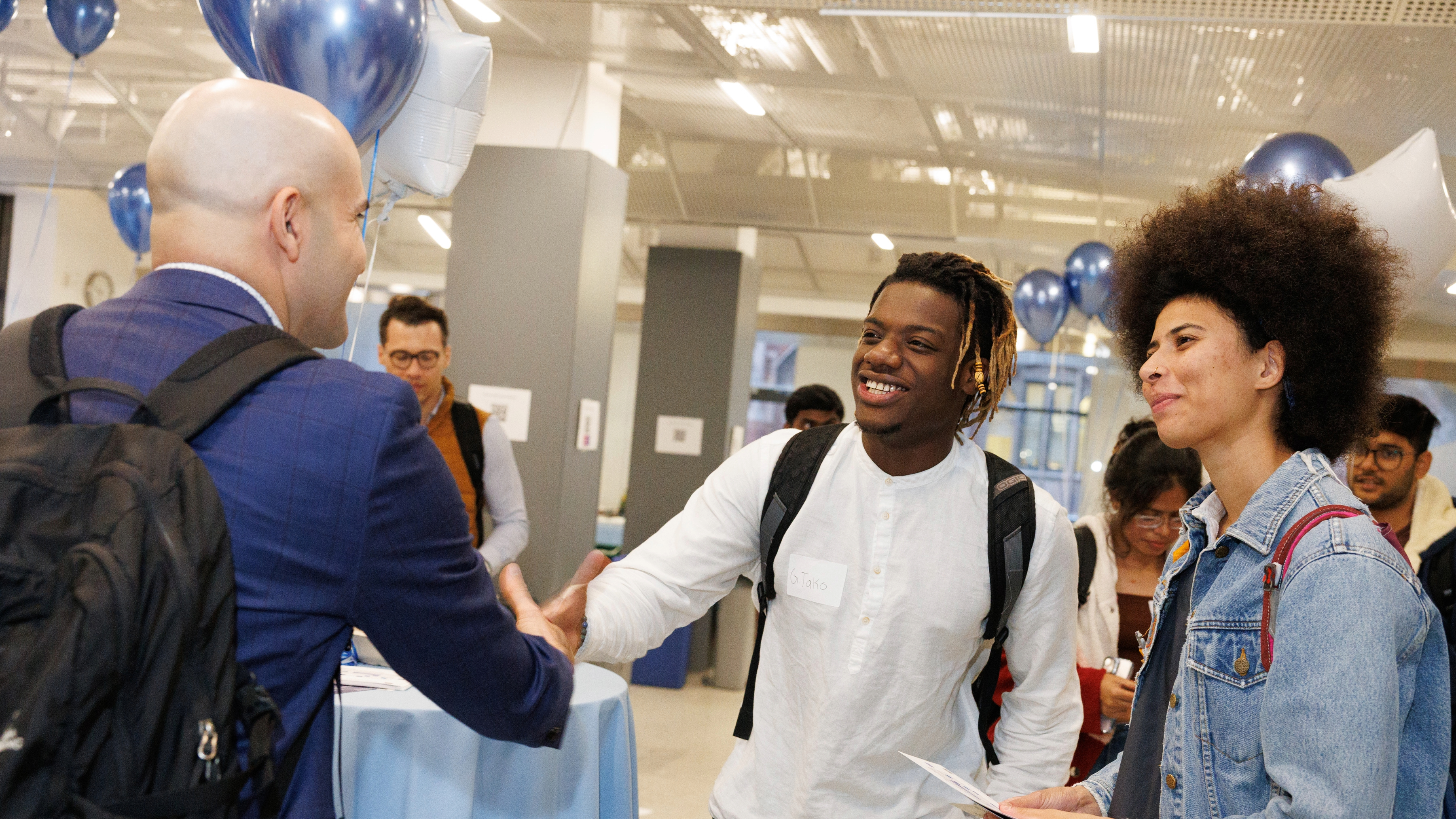 Faculty and students shake hands at a Columbia Engineering event