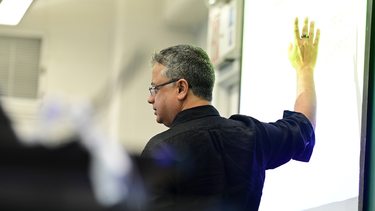 Vishal Misra gesturing towards a projector screen