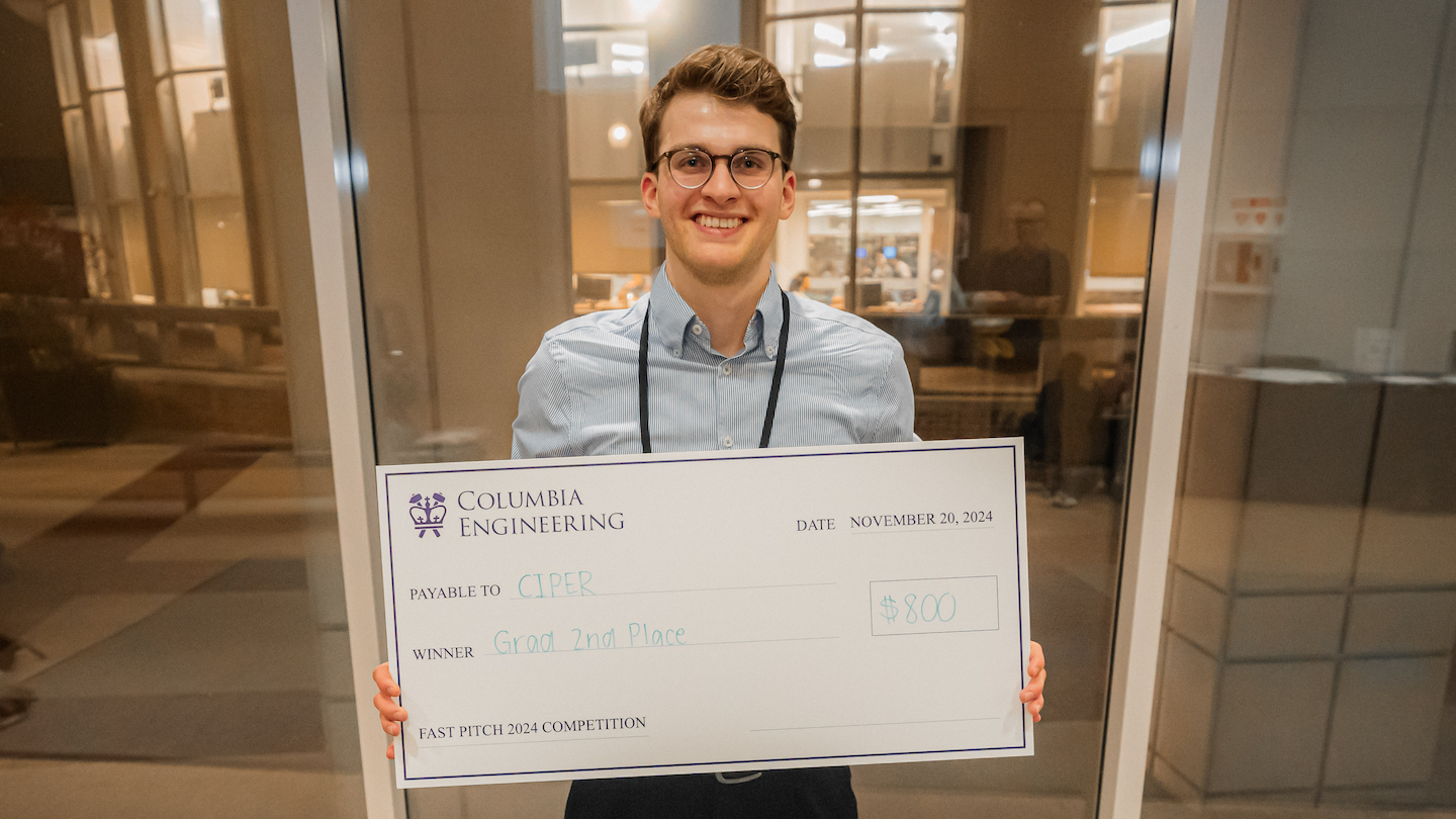 A student holding up a giant $800 check payable to CIPER