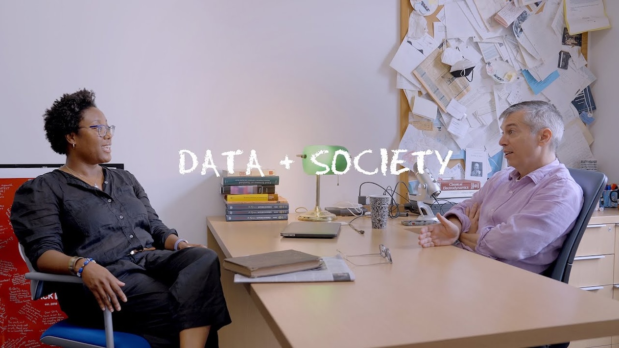 The text "Data + Society" overlays Chris Wiggins and Courtney Cogburn conversing in an office