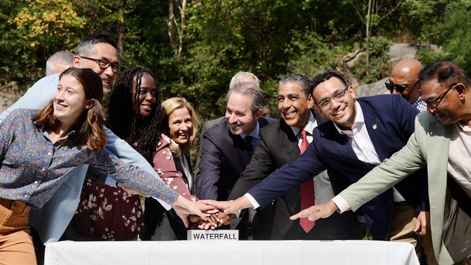 Participants in Friday's event in Morningside Park gather to ceremonially hit a button to turn the park's waterfall on.