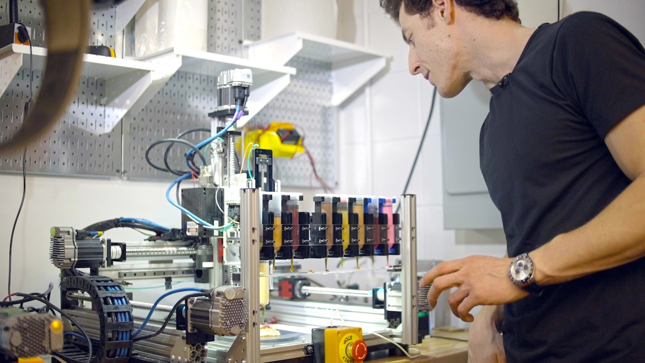 A researcher standing next to their 3D-printing food machine