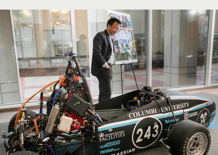 A person standing next an electric formula racing car.