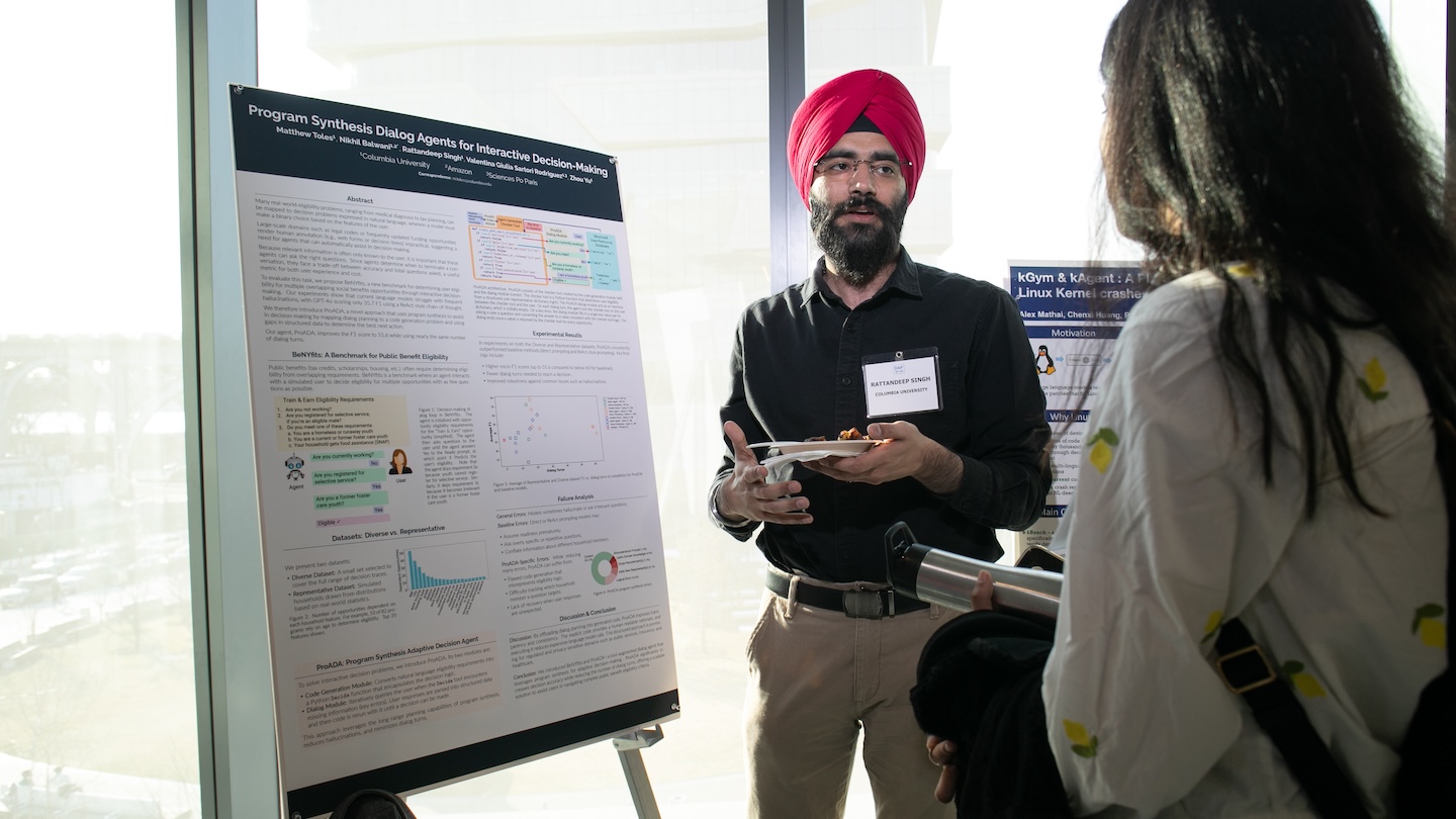 Two people speaking in front of a research presentation board