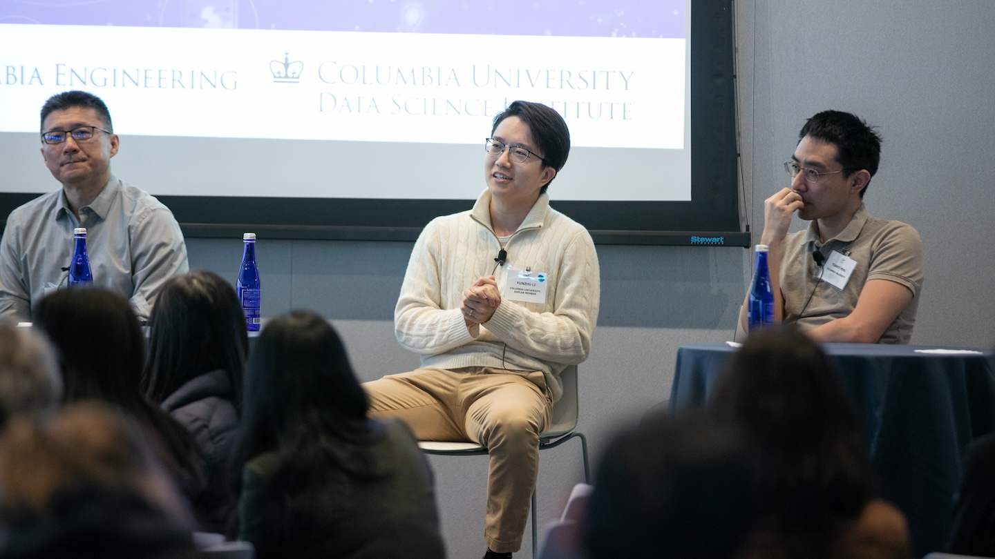 Three panelists sit on stage