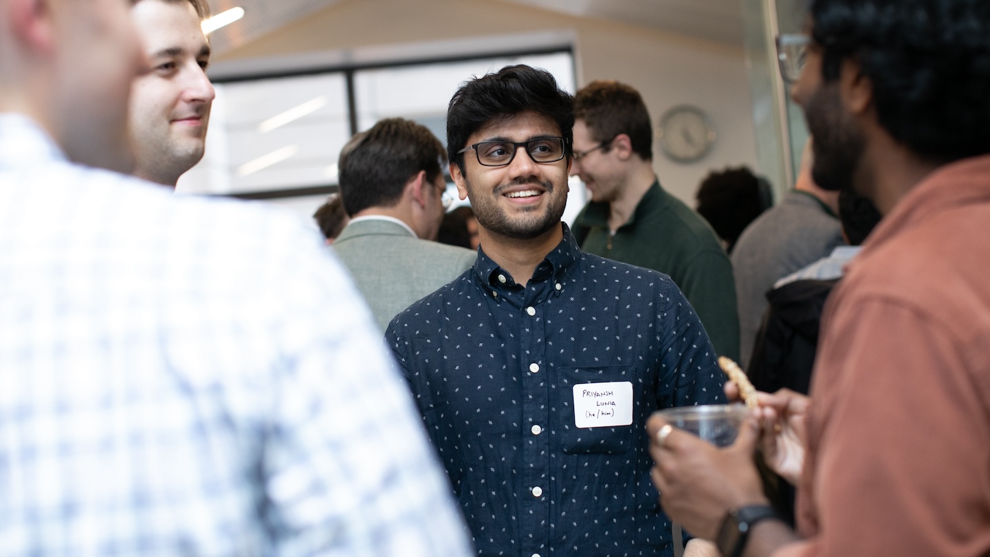 A person speaking with three others among a crowded room