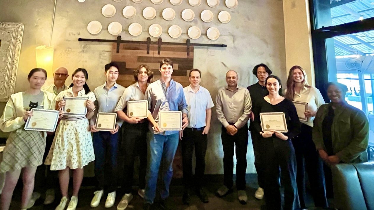 Eleven people posing for a photo. Seven of them hold certificates