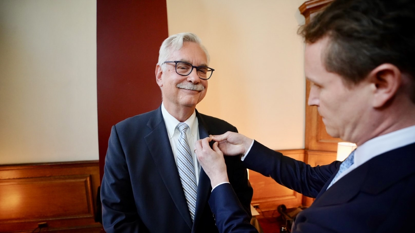 John Szymanski receiving a pin in his jacket lapel from CEAA President Reid Ellison