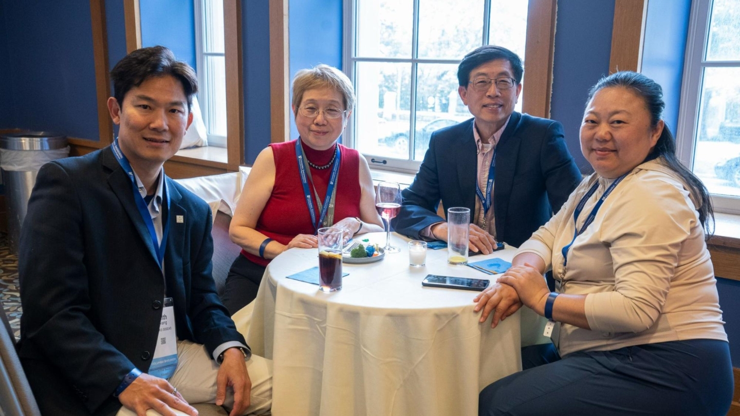 Four Columbia Engineering alumni sitting around a table and posing for a photo