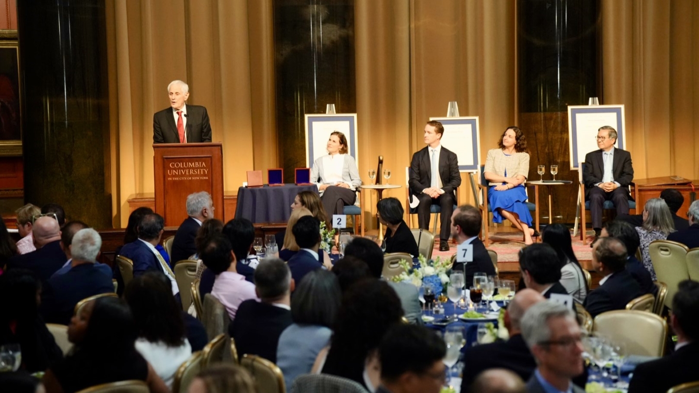 Zvi Galil standing at a podium and addressing a crowded banquet hall.