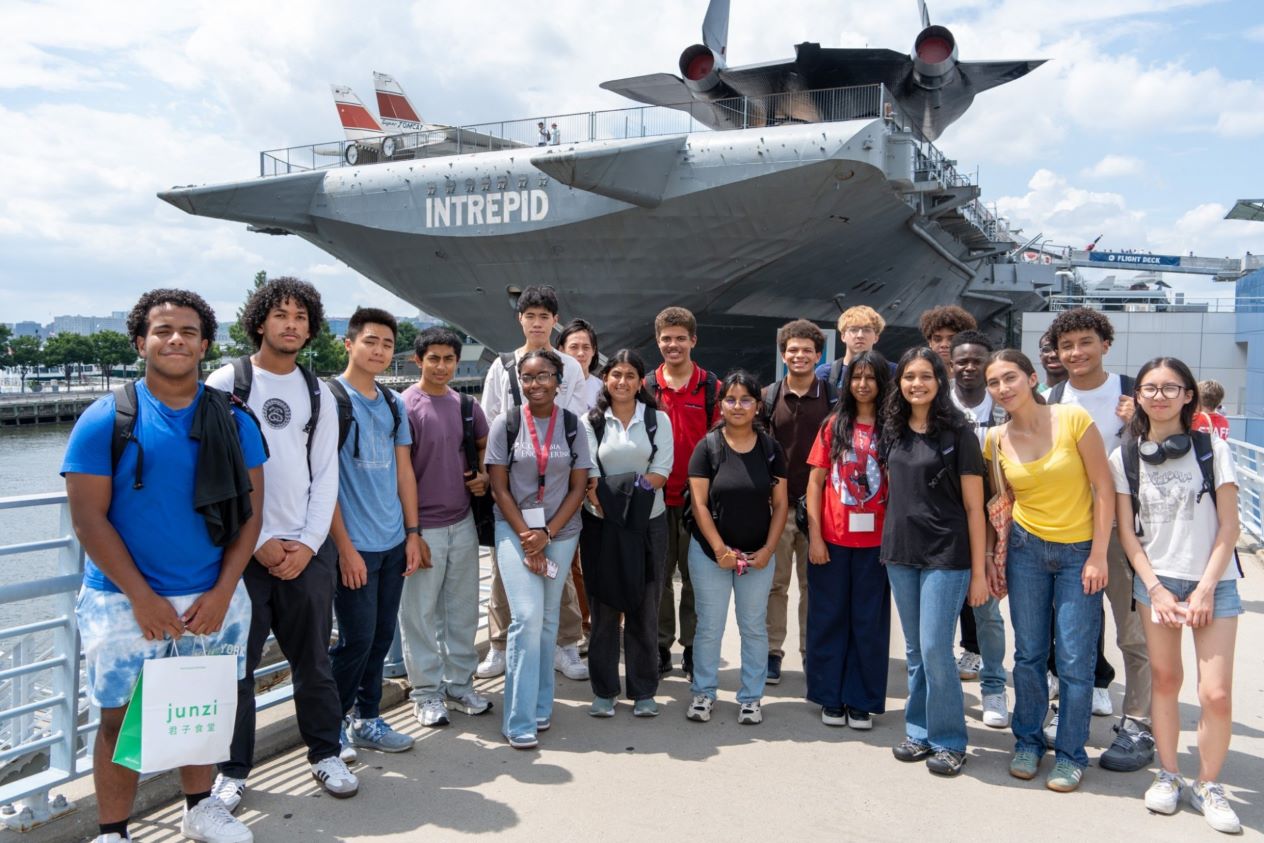 group of students standing in front of the intrepid