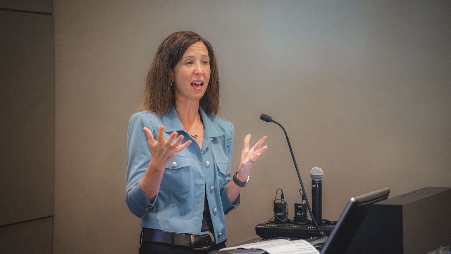 speaker gesturing while speaking into a podium microphone