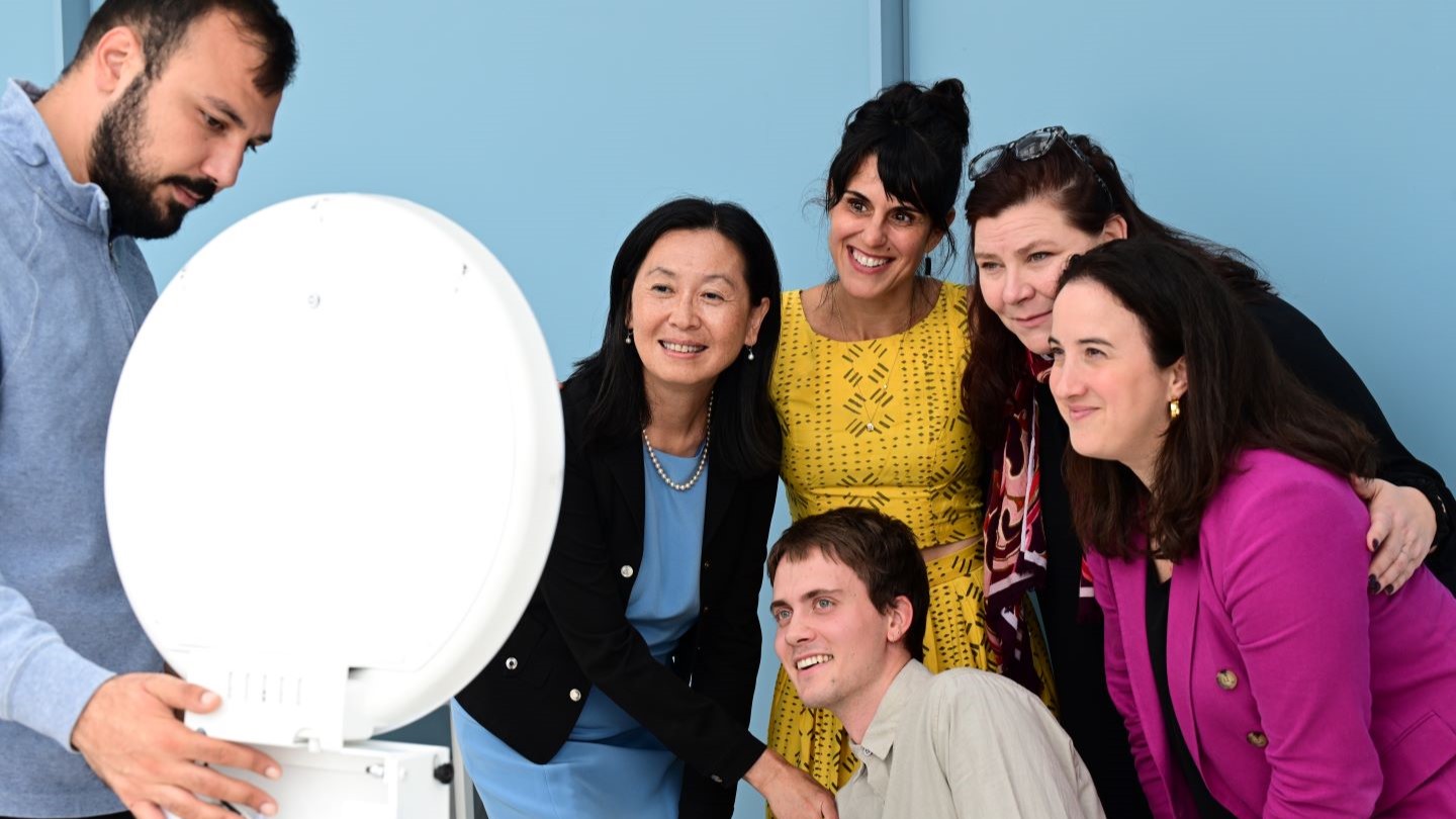 people posing for a photo in front of a large circular lense