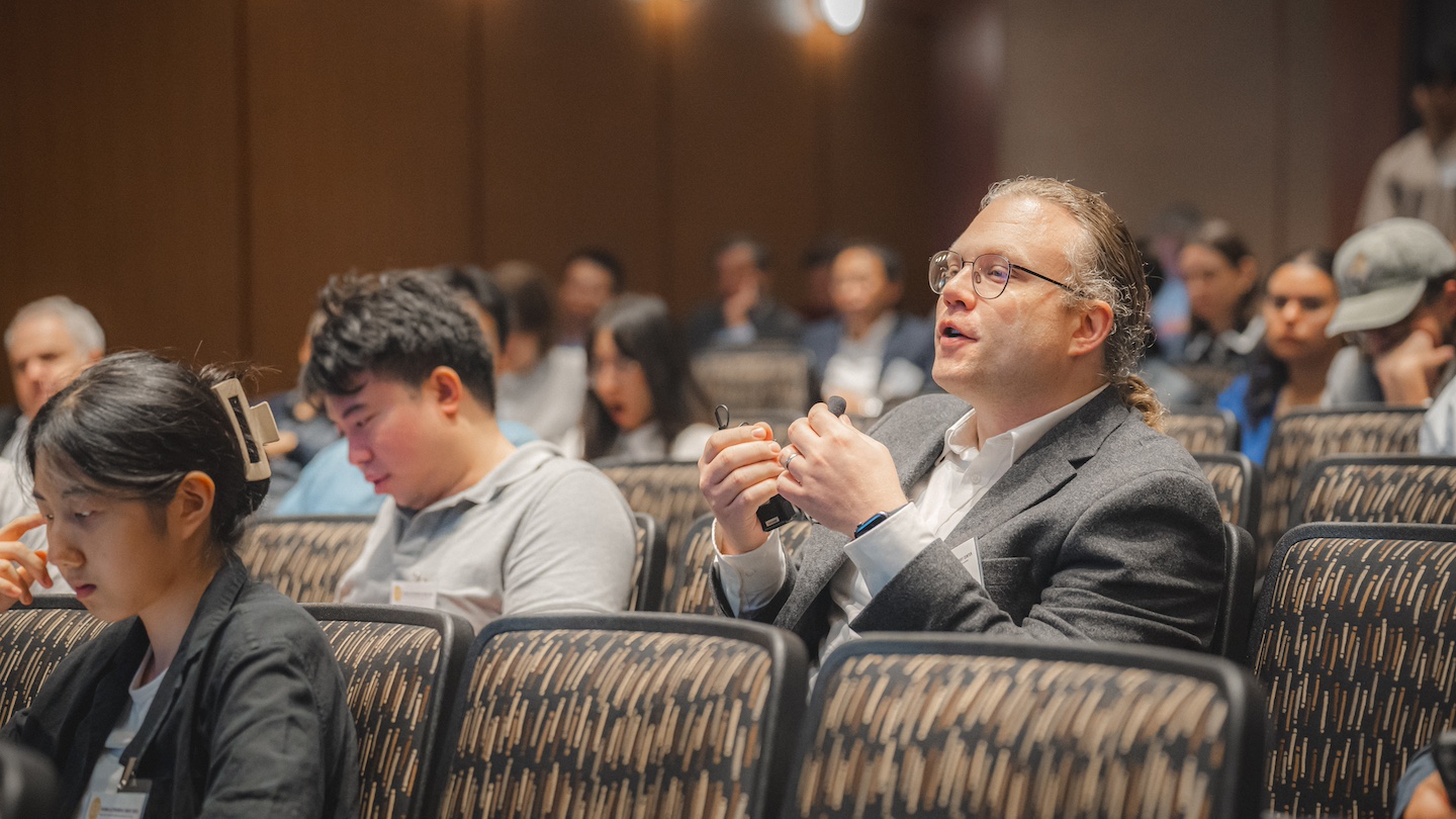 audience seated in an auditorium-like room, with one speaking