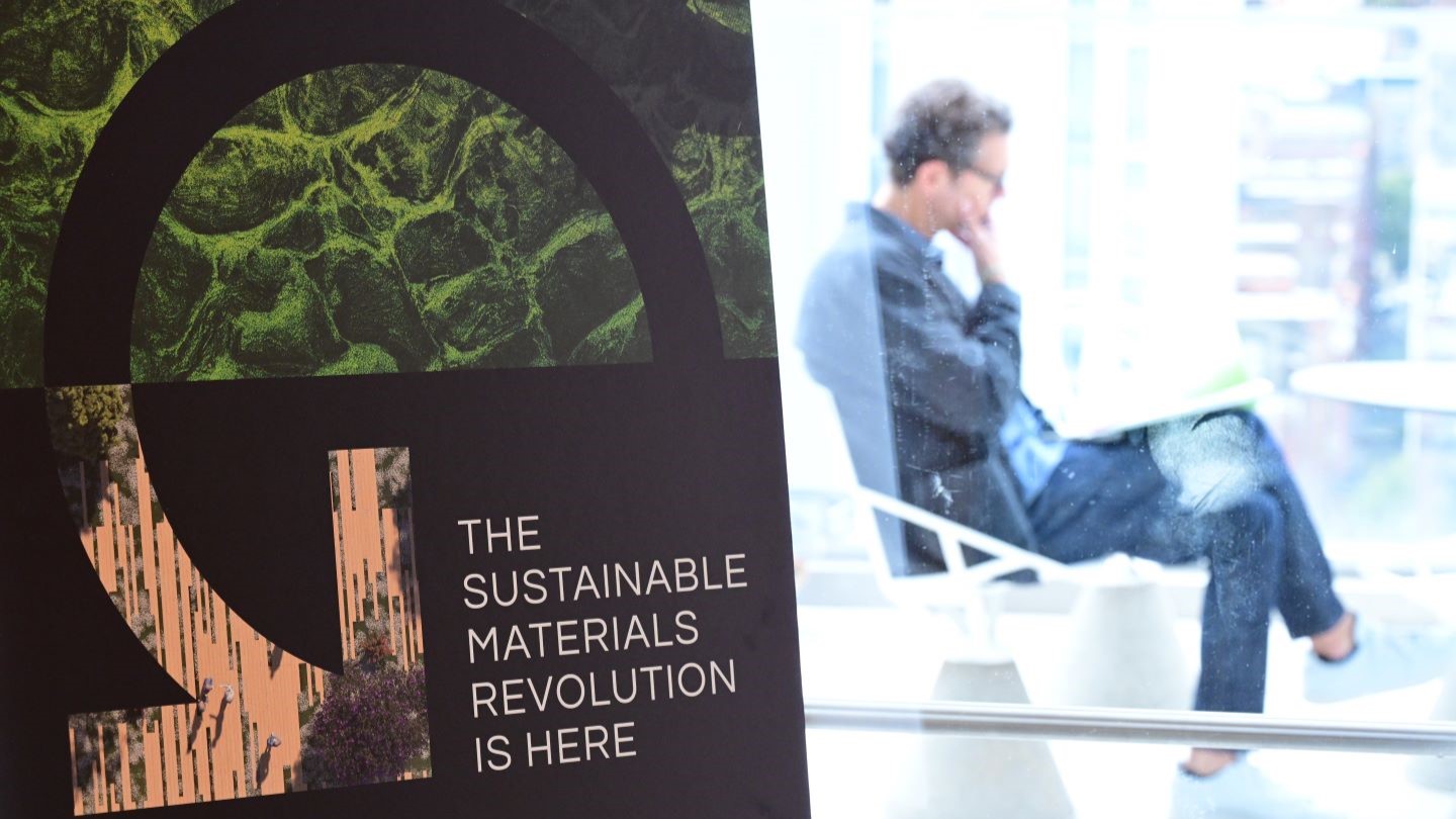 sign reading "sustainable materials revolution is here" with a person sitting in the background