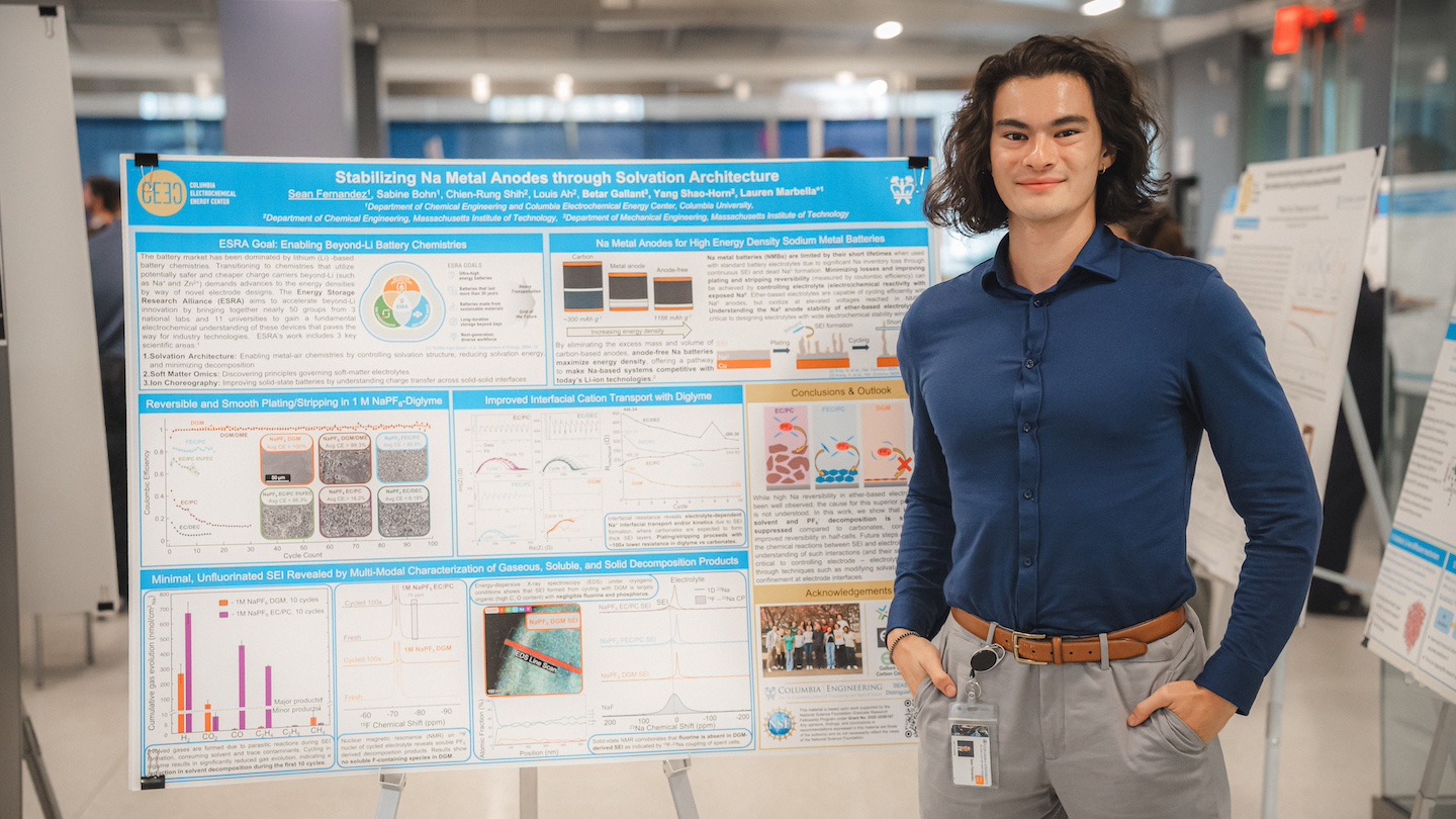 research presenter standing next to their poster