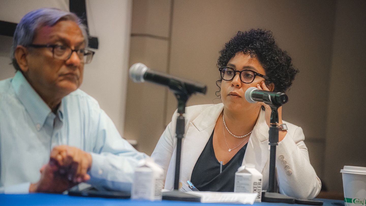 two speakers sat next to each other, microphones faced at them