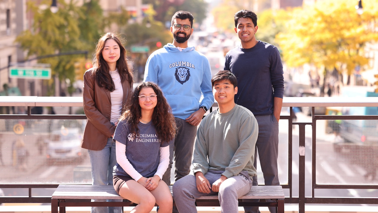 group of 5 students gathered by a bench