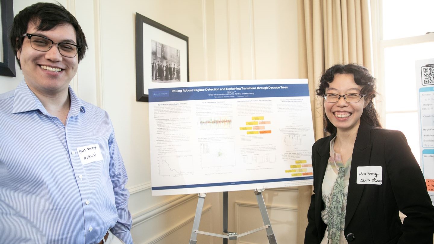 two researchers standing next to their presentation