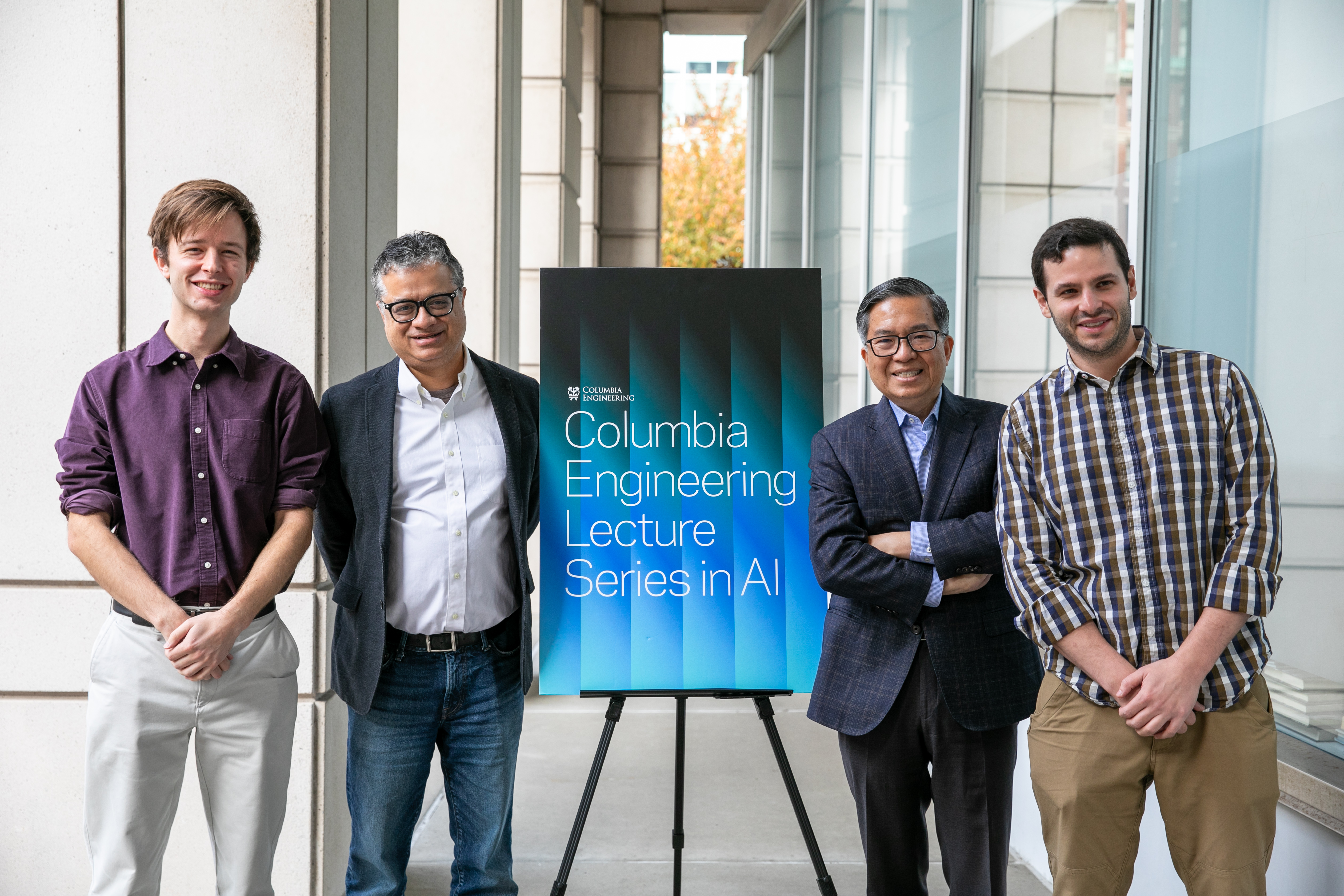 (L to R): Computer Science Assistant Professor John Hewitt, Vice Dean of Computing and AI Vishal Misra, Dean Shih-Fu Chang, and Electrical Engineering Assistant Professor Micah Goldblum standing next to a "Columbia Engineering Lecture Series in AI" banner