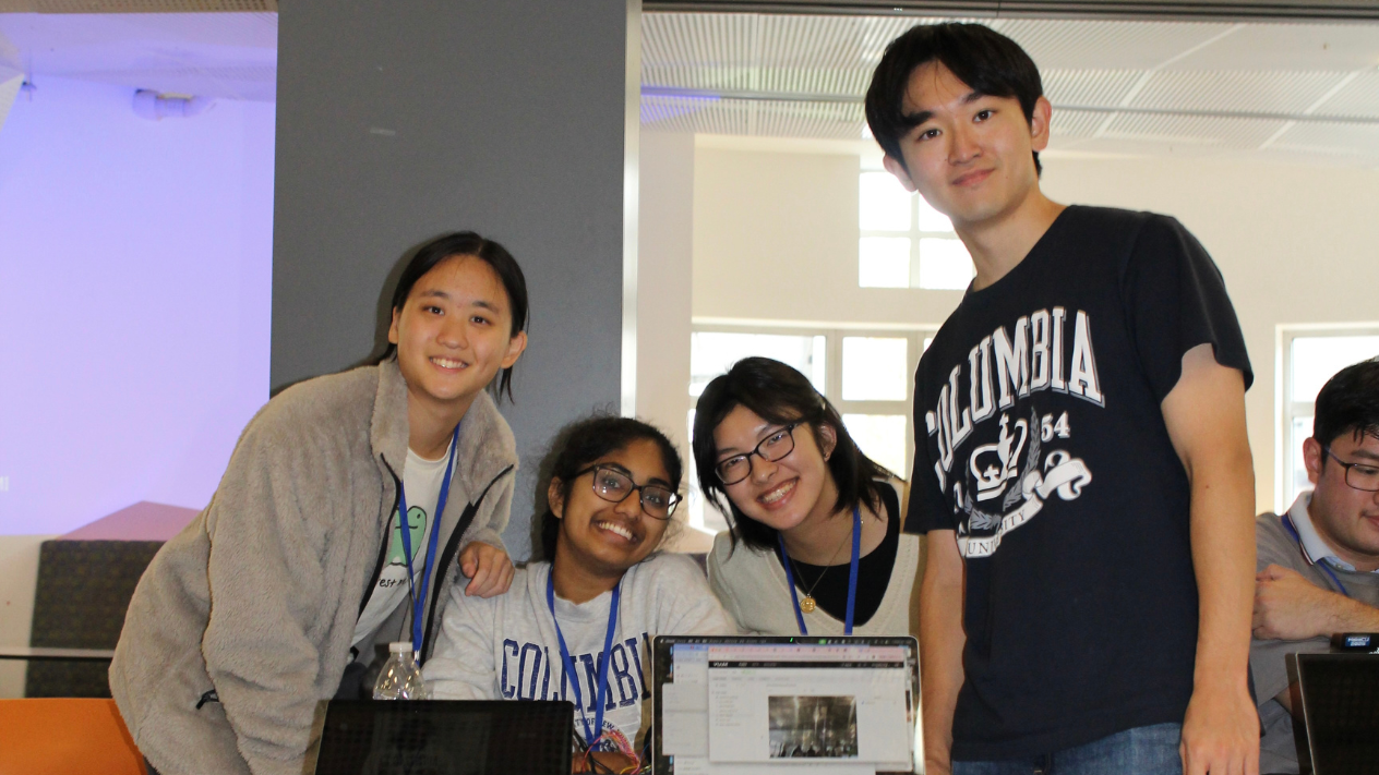 Four Columbia students posing for a photo with their laptop