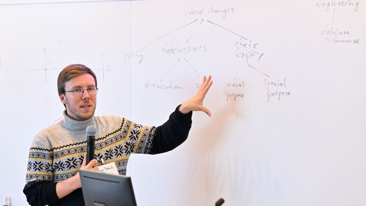 speaker with microphone, pointing at words on a whiteboard
