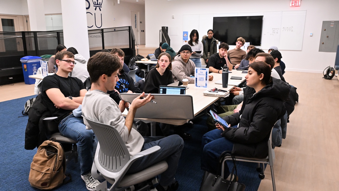 students gathered together at large table with laptops