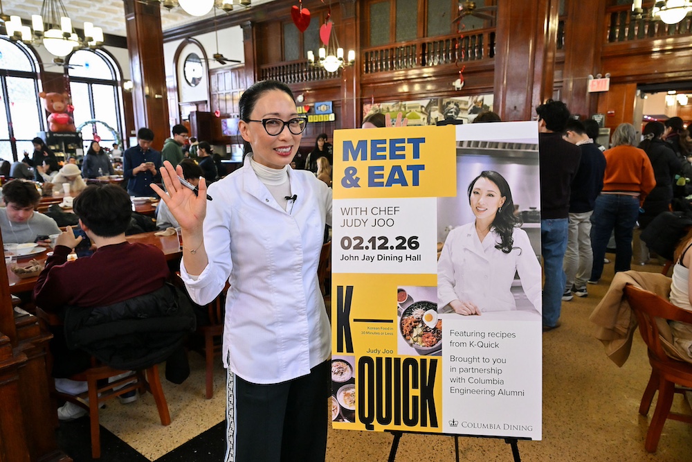 Judy Joo standing next to a "Meet & Eat" banner