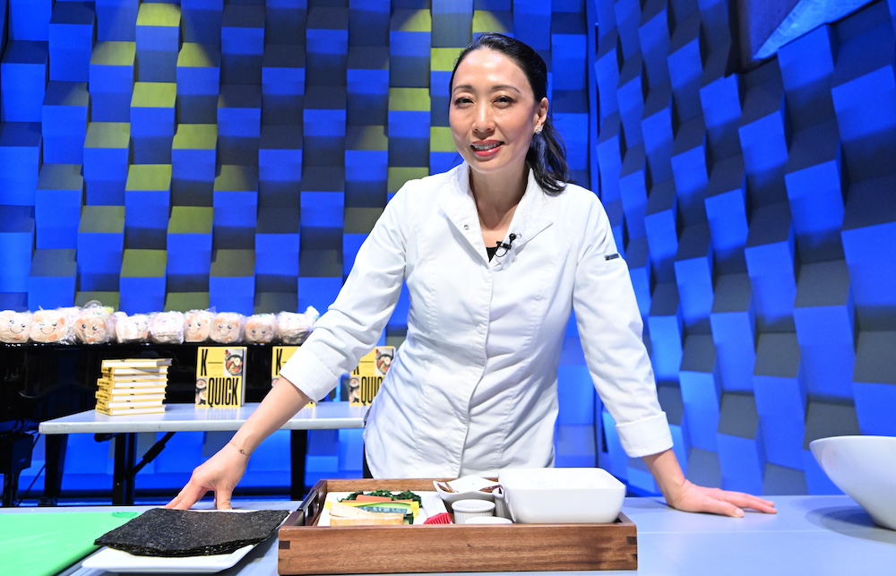 Judy Joo posed behind a table with kimbap ingredients