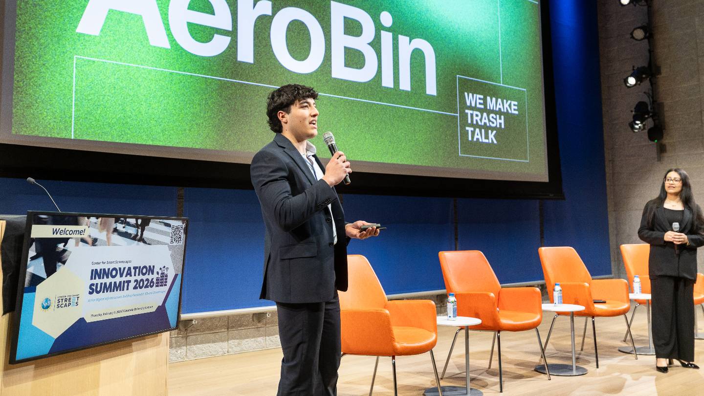 Two presenters on stage holding microphones. The projector screen behind them reads "AeroBin, we make trash talk"