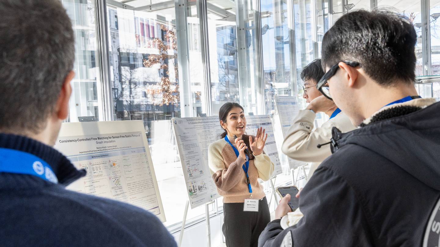 A presenter sharing their research poster with three others