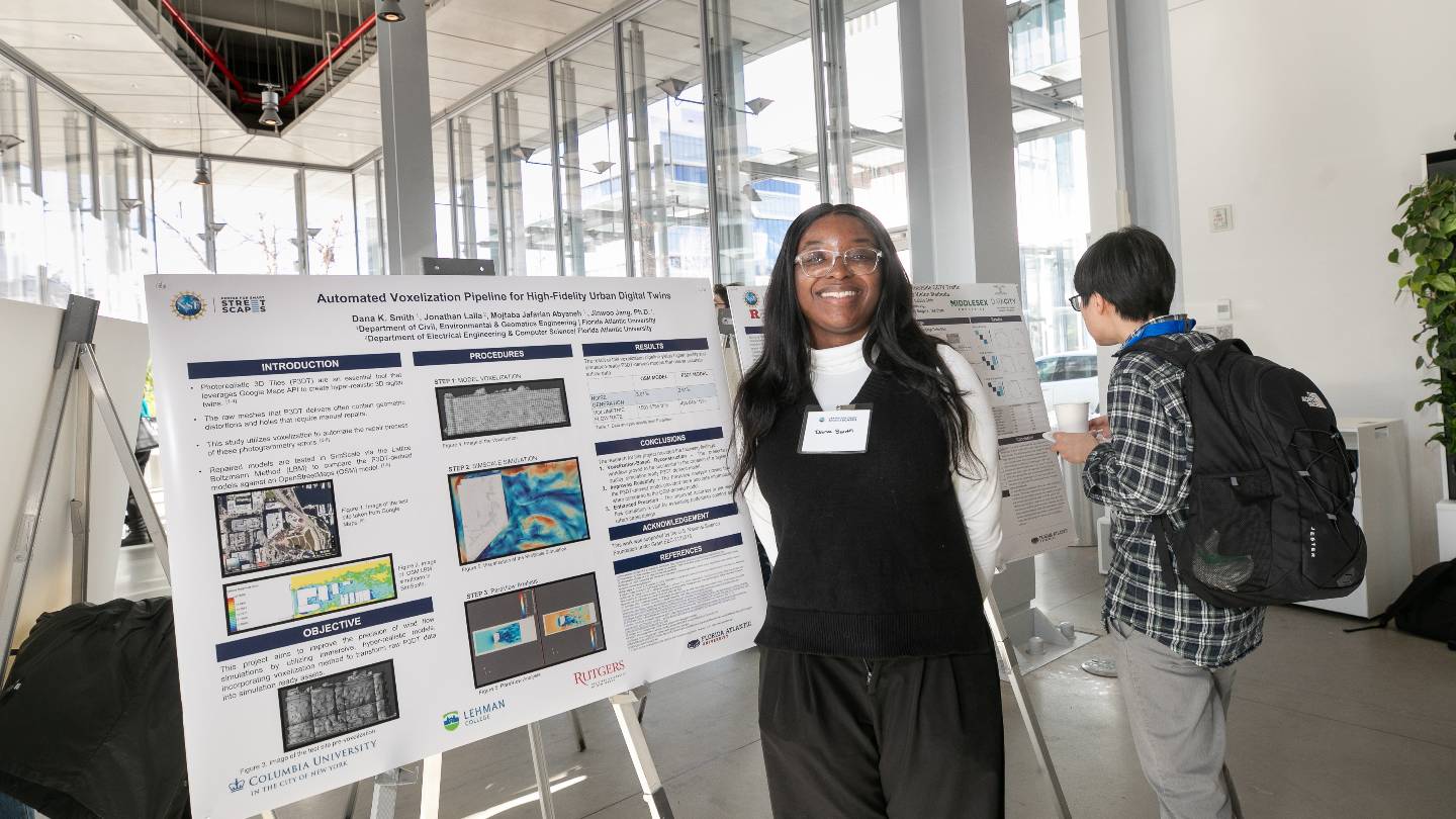 A person smiling next to a research poster. The poster title reads "Automated Voxelization Pipeline for High-Fidelity Urban Digital Twins"