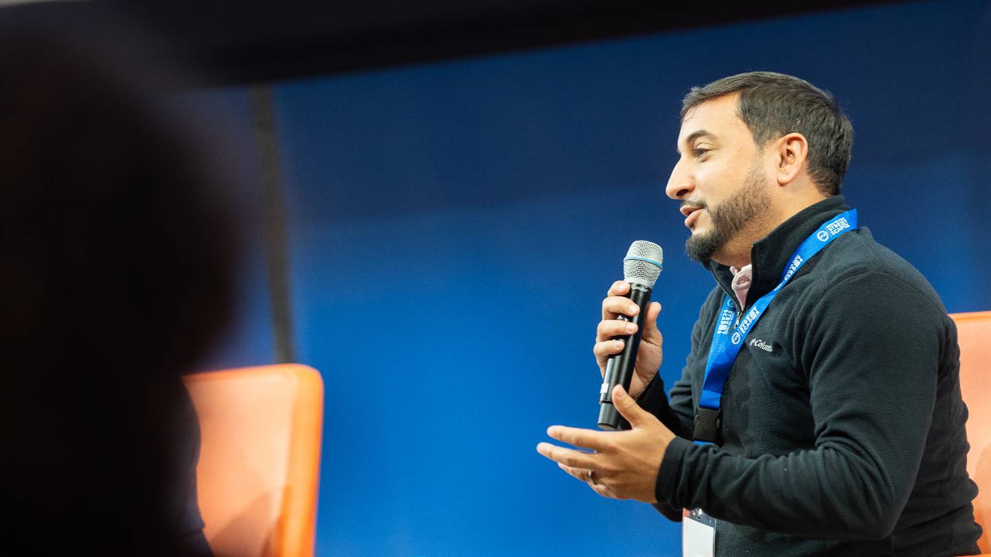 A person on-stage speaks into a handheld microphone