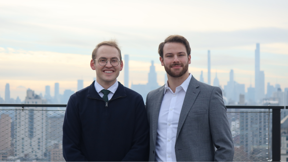 Two people posing for a photo in front of the New York City skyline