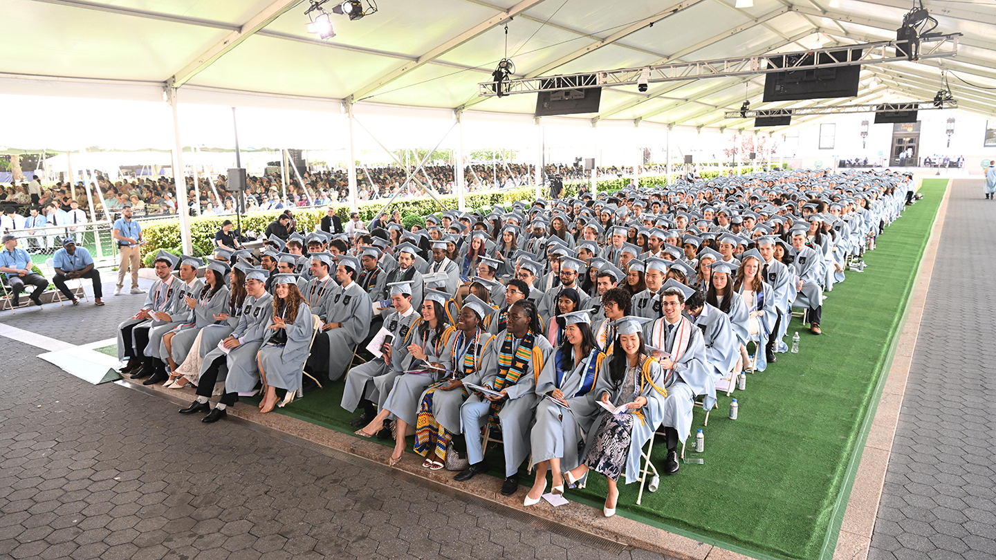 Wide view of Columbia Engineering students in light-blue caps and gowns seated in rows under a large tent during Columbia Engineering Class Day 2026.