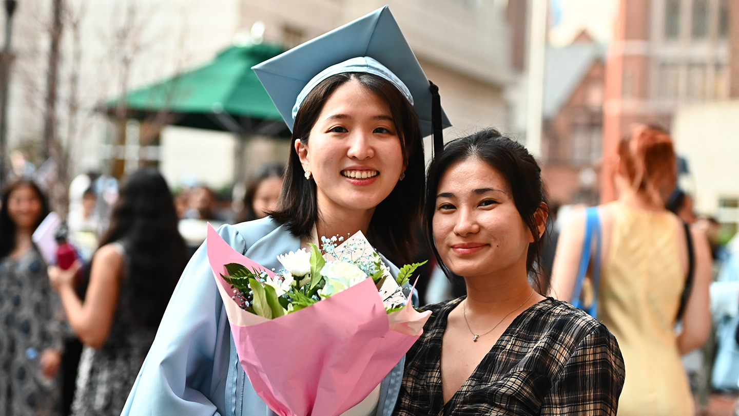 A Columbia Engineering student posing for a photo with a woman while holding a bouquet of flowers.