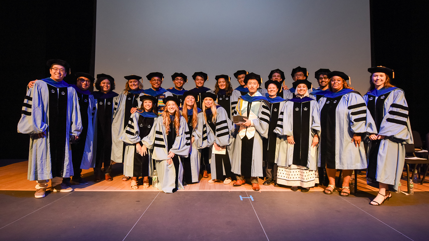 A large group of Columbia Engineering doctoral graduates in regalia posing for a photo in two rows