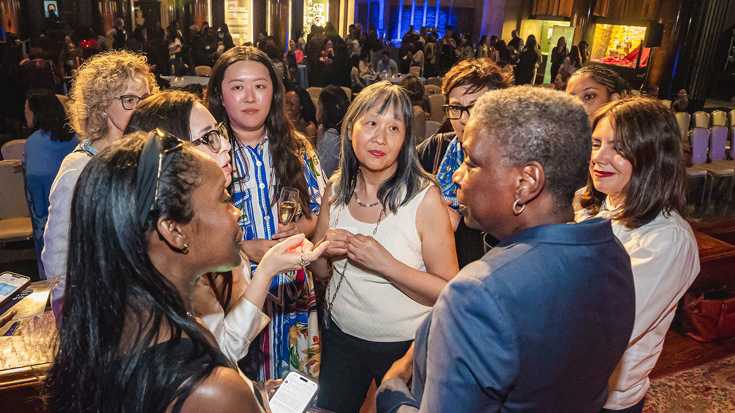 Attendees mingle and talk in a crowded reception hall during a networking event.