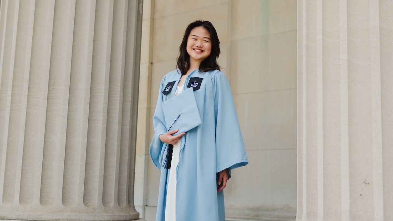 A woman posing for a photo in Columbia University graduation regalia