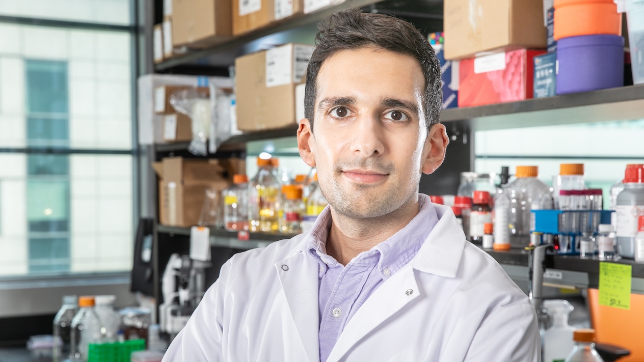 Santiago Correa wearing a lab coat in a lab lined with flasks and test tubes