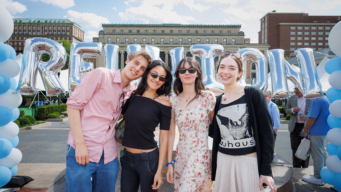 Four Columbia Engineering alums pose outdoors in front of large silver “REUNION” balloon letters on Columbia’s campus, framed by blue-and-white balloons.