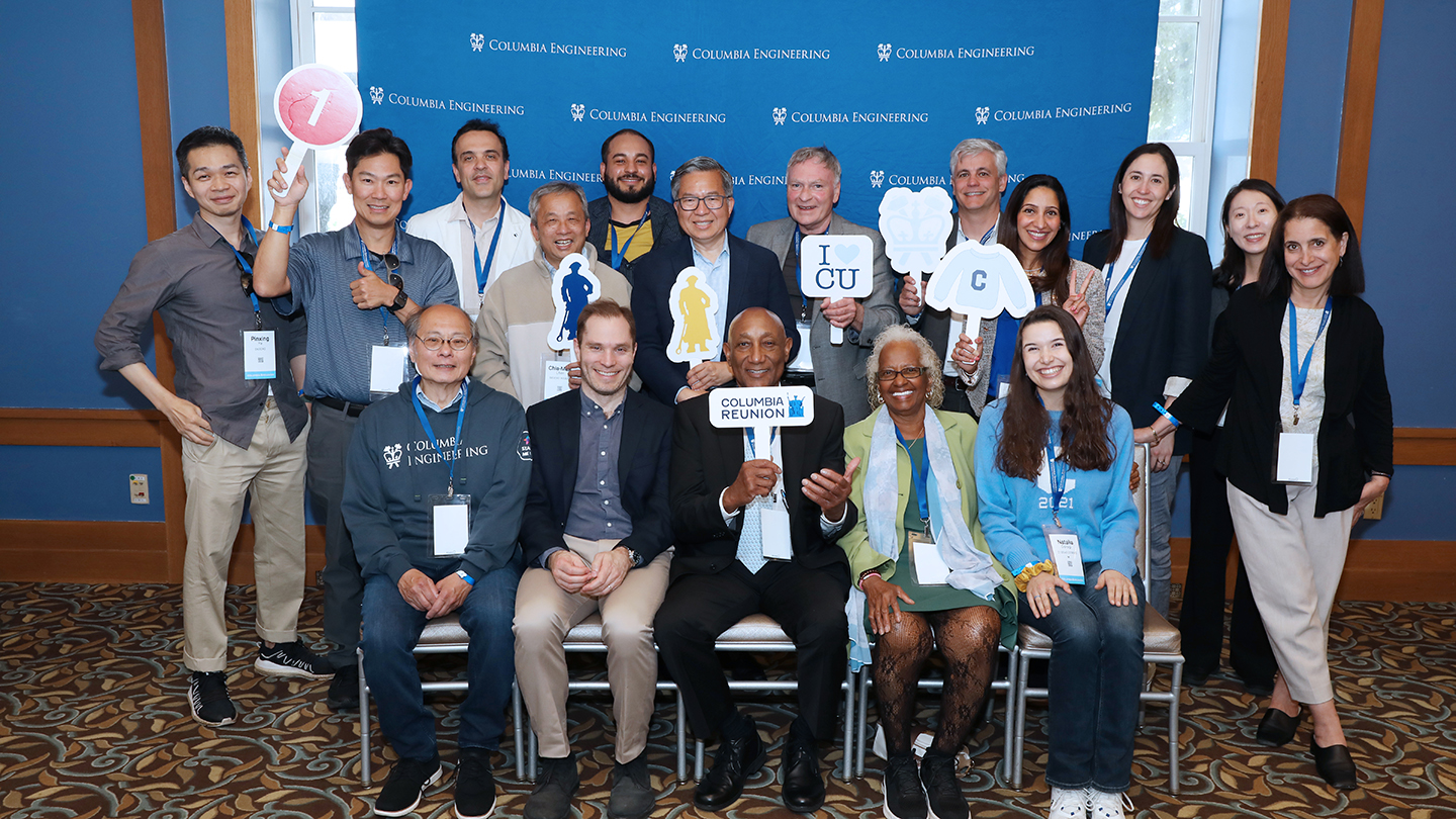 Group photo of Columbia Engineering alumni and Dean Shih-Fu Chang in front of a “Columbia Engineering” step-and-repeat backdrop, holding reunion-themed props including “Columbia Reunion” and “I ♥ CU” signs.