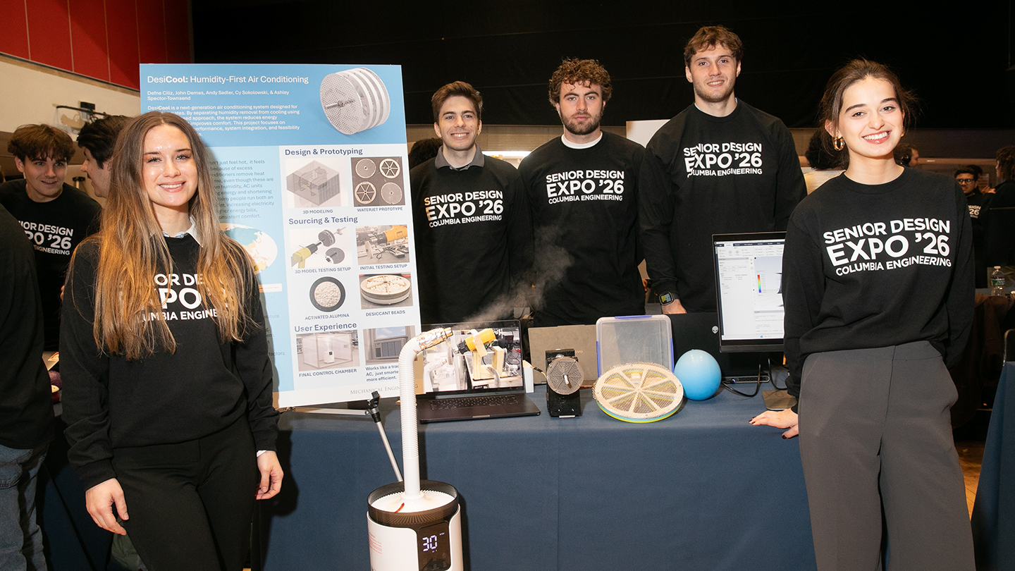 A team in “Senior Design Expo ’26” shirts stands behind a table display for “DesiCool: Humidity-First Air Conditioning,” with prototypes and a monitor.