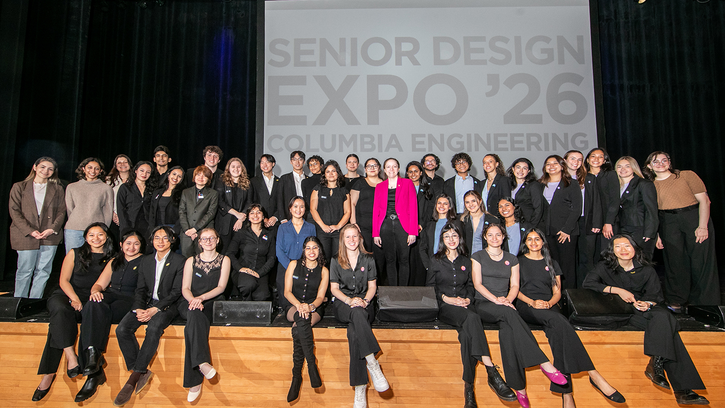 Large group photo of students on a stage in front of a screen reading “Senior Design Expo ’26, Columbia Engineering.”