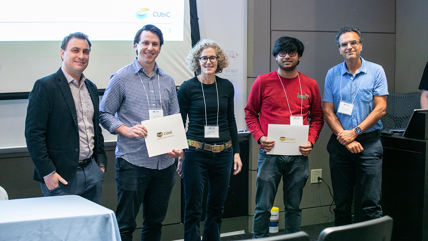 Five CUbiC participants pose for a photo in a lecture room; two hold CUbiC certificates.