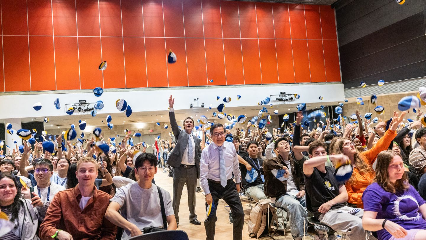 Dean Shih-Fu Chang and Barclay Morrison III stand among attendees as blue-and-white beanies fly overhead.